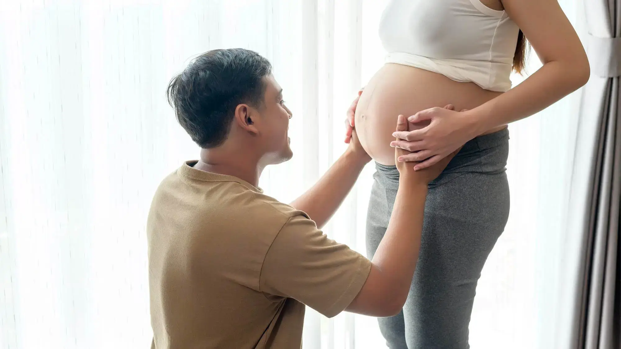老公輕撫懷孕妻子孕肚象徵夫妻共同迎接新生命