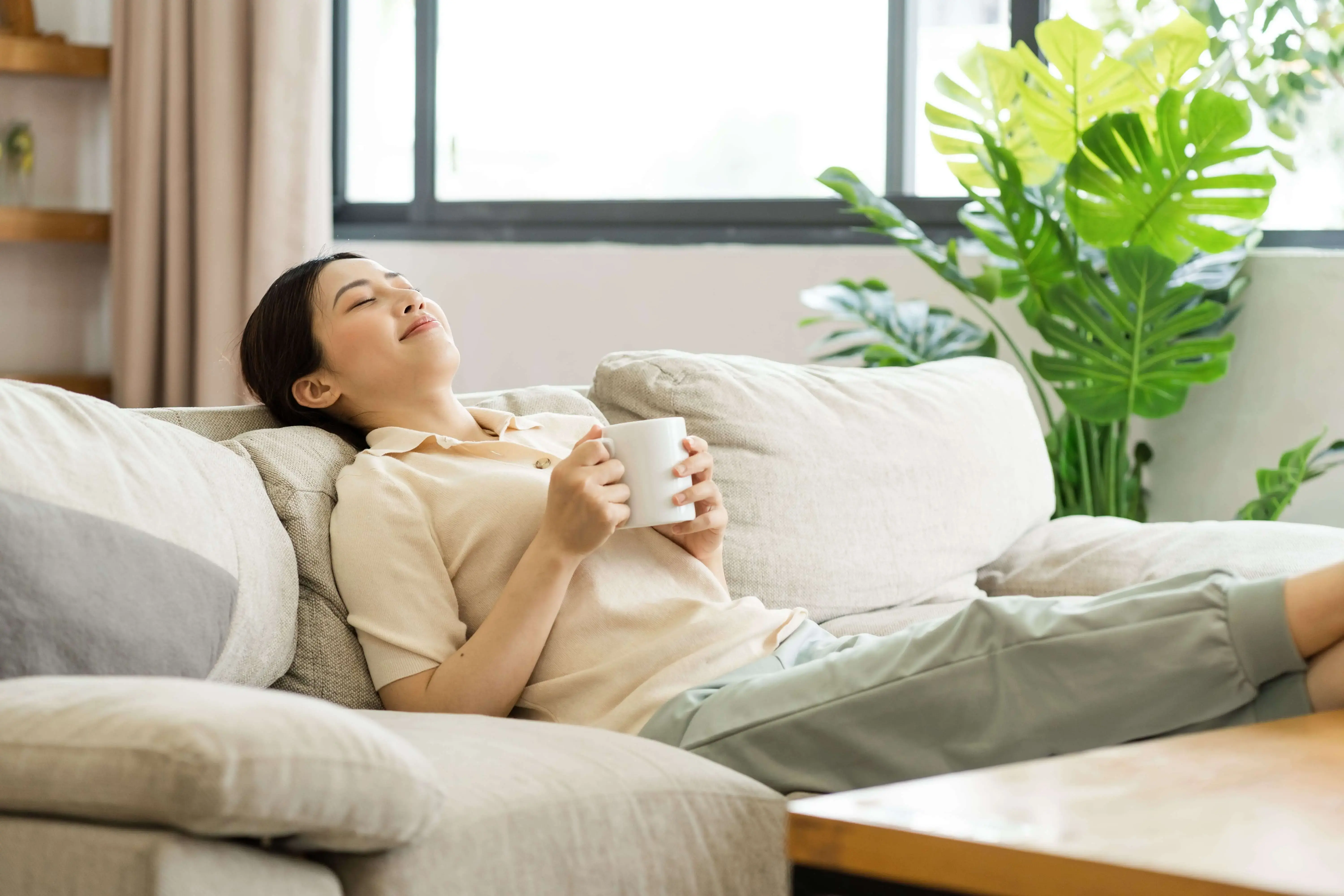 Woman relaxing on a sofa with tea after failed IVF cycles, focusing on emotional recovery and stress relief